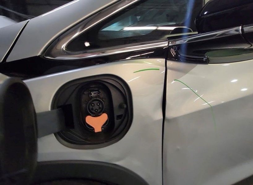 Silver electric vehicle charging port open, showing charging socket.