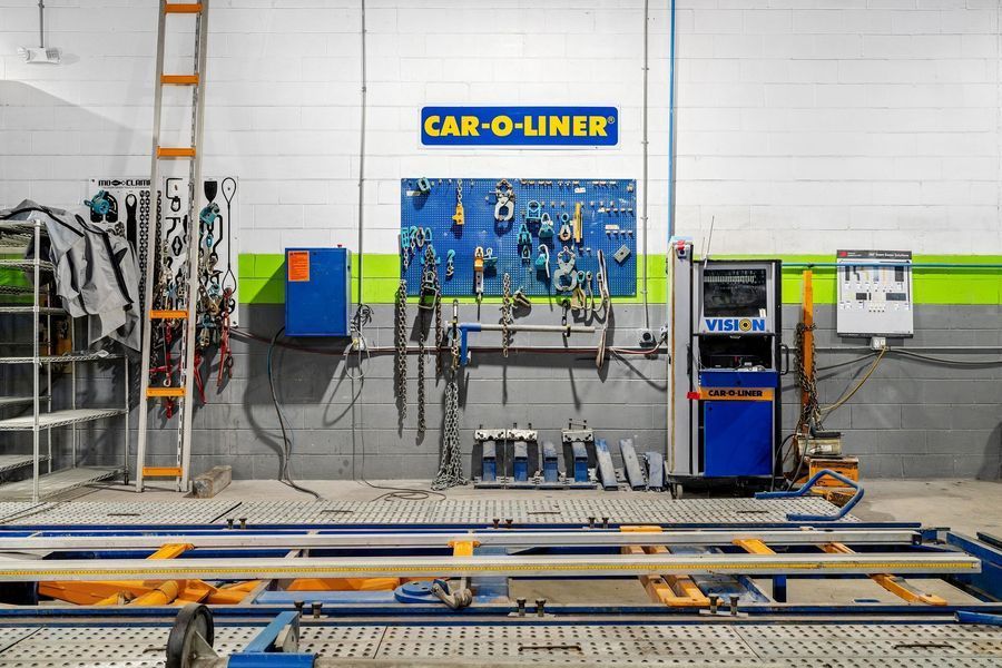 Auto body repair shop interior with Car-O-Liner equipment, tools, and a straightening rack.
