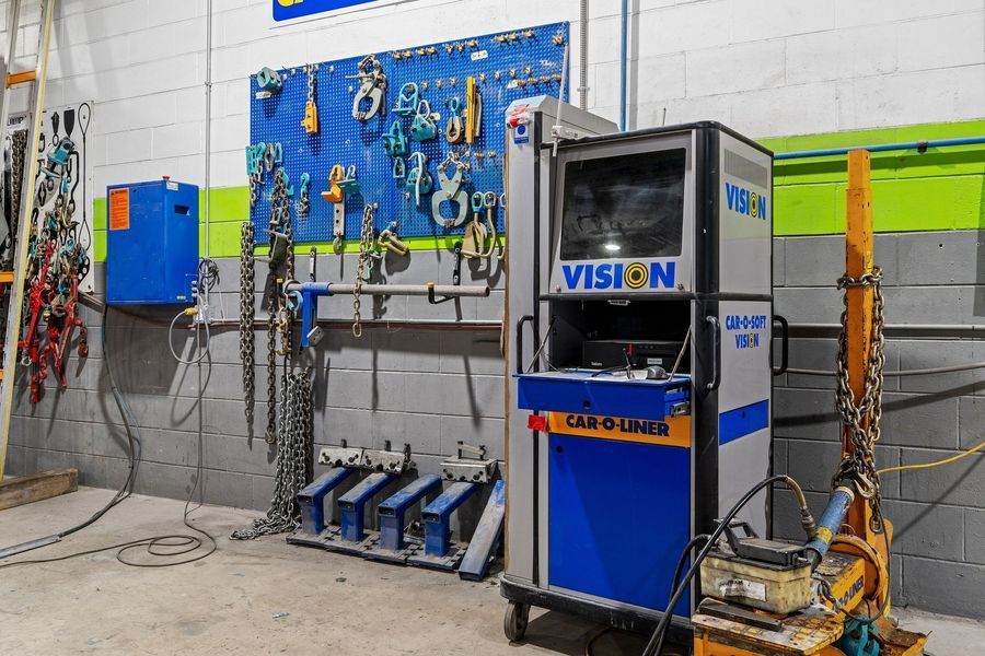 Car repair shop with tools hanging on a blue pegboard, and a Vision Car-O-Liner machine.