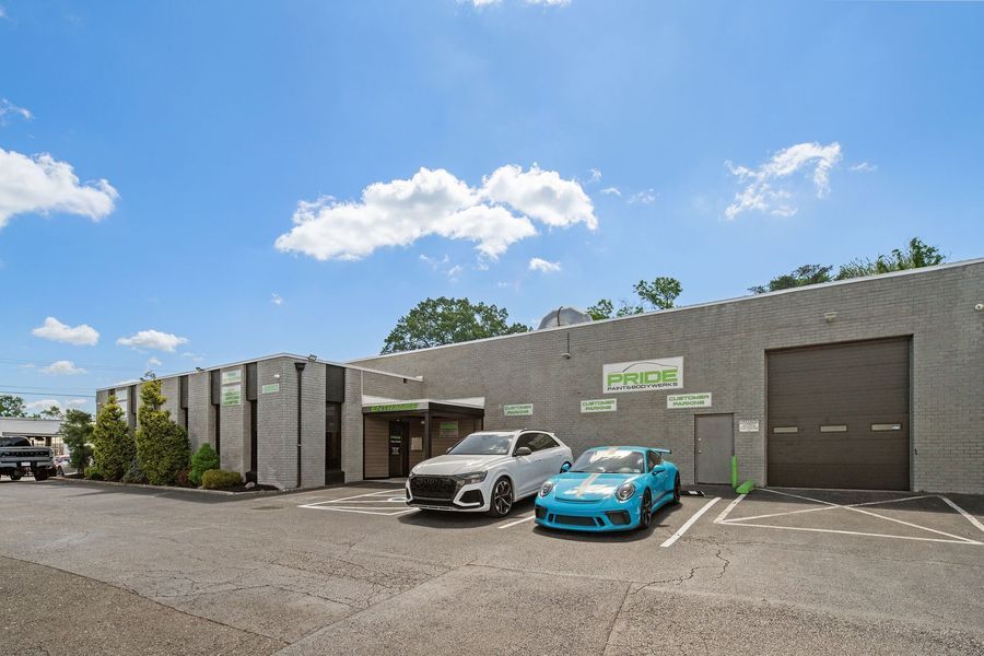 Gray commercial building with two parked cars on a sunny day.