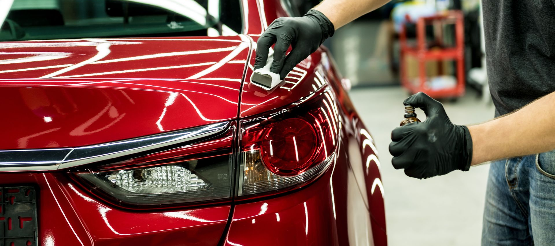 Mechanic polishing a red car’s front fender in an auto body shop