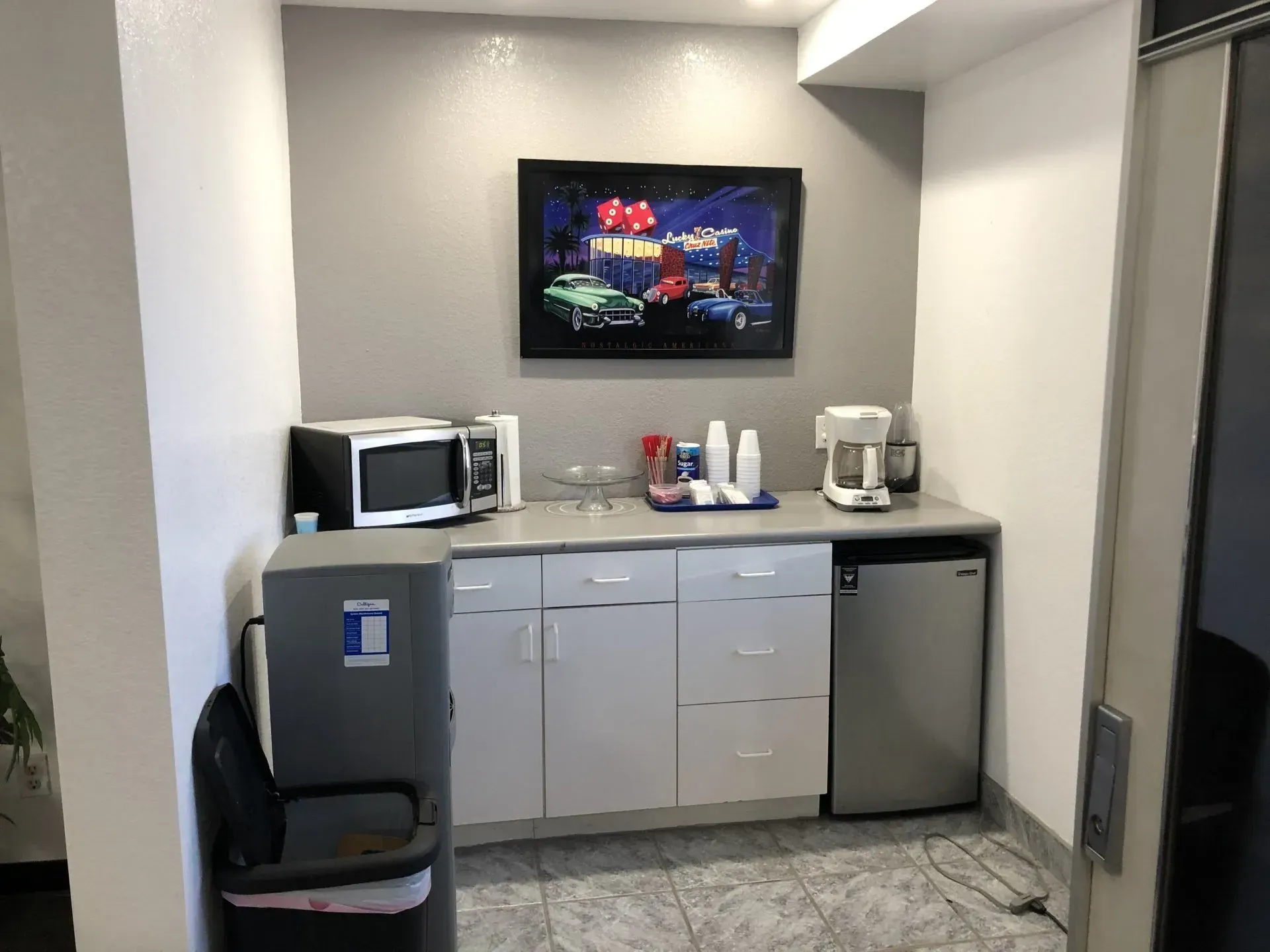 Break room kitchenette with microwave, coffee maker, mini fridge, and wall-mounted TV above the counter
