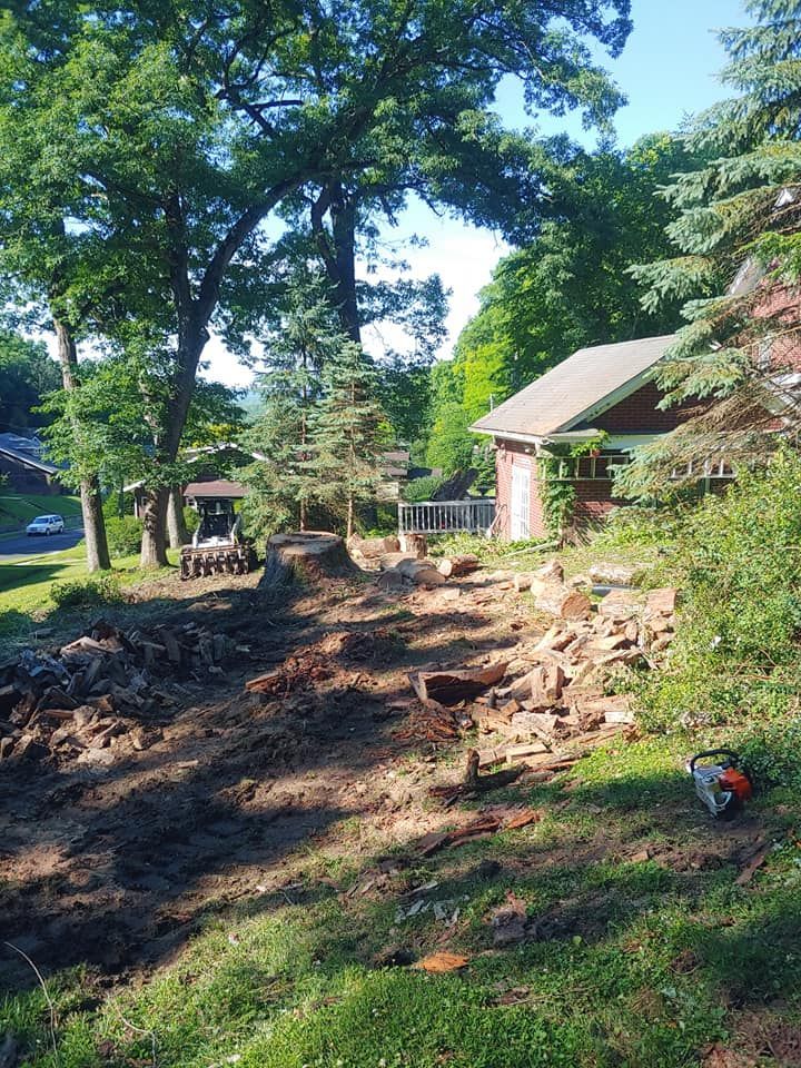A tractor is driving down a dirt road in front of a house.