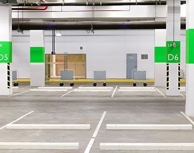 An empty parking garage with green signs on the pillars.