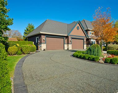 A large house with two garage doors and a long driveway leading to it.