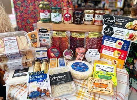 Assorted packaged breads, cheeses, jams, and pantry foods displayed on a market table