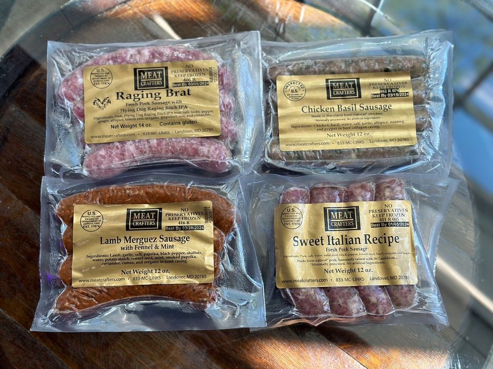 Four packaged raw meats in clear plastic bags on a countertop, labeled sirloin steak, pork, chicken breast, and sausage