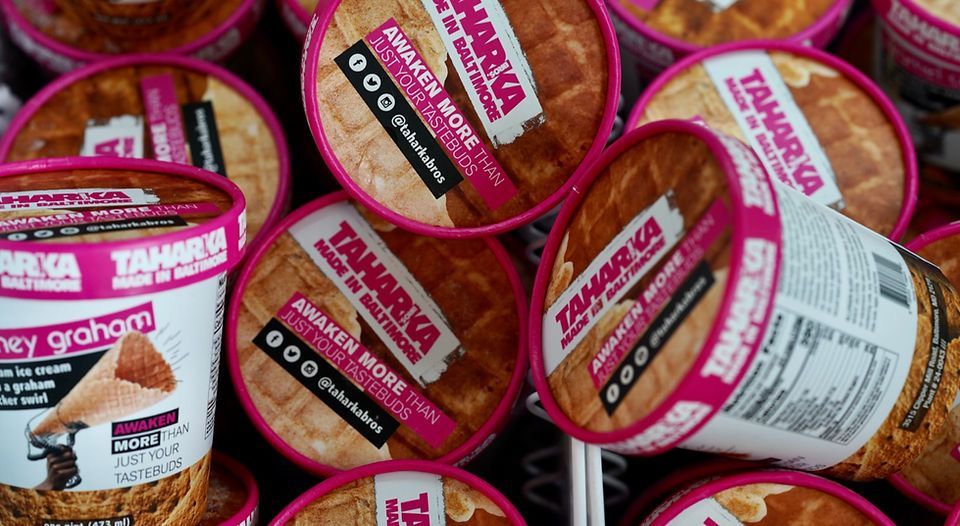 Assorted pink-labeled tahini tubs stacked together in a store display