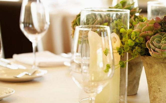 Wine glasses and a floral centerpiece on a softly lit dining table