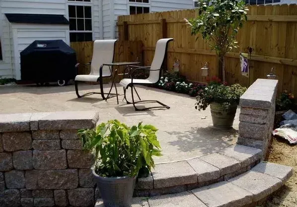 Patio with stone retaining walls, seating, grill, and plants.