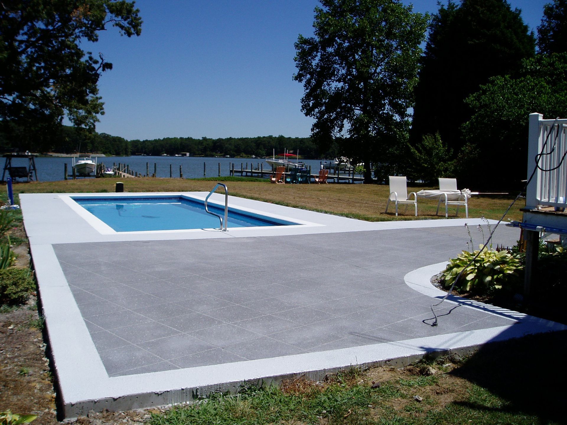 Concrete patio with a pool overlooking a body of water.