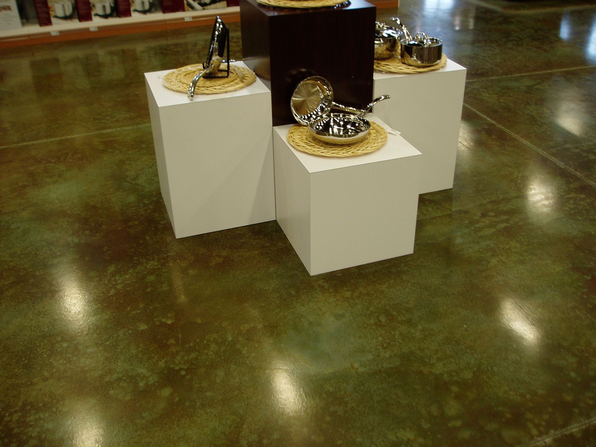 Silverware display on white pedestals, set on a shiny green and brown floor.
