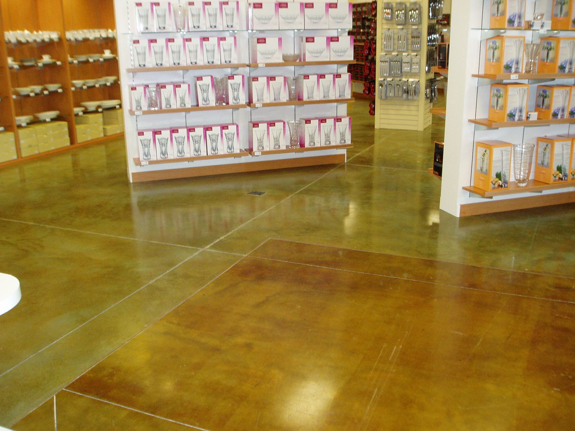 Polished concrete store floor with merchandise displays. Golden brown hue with light reflections.