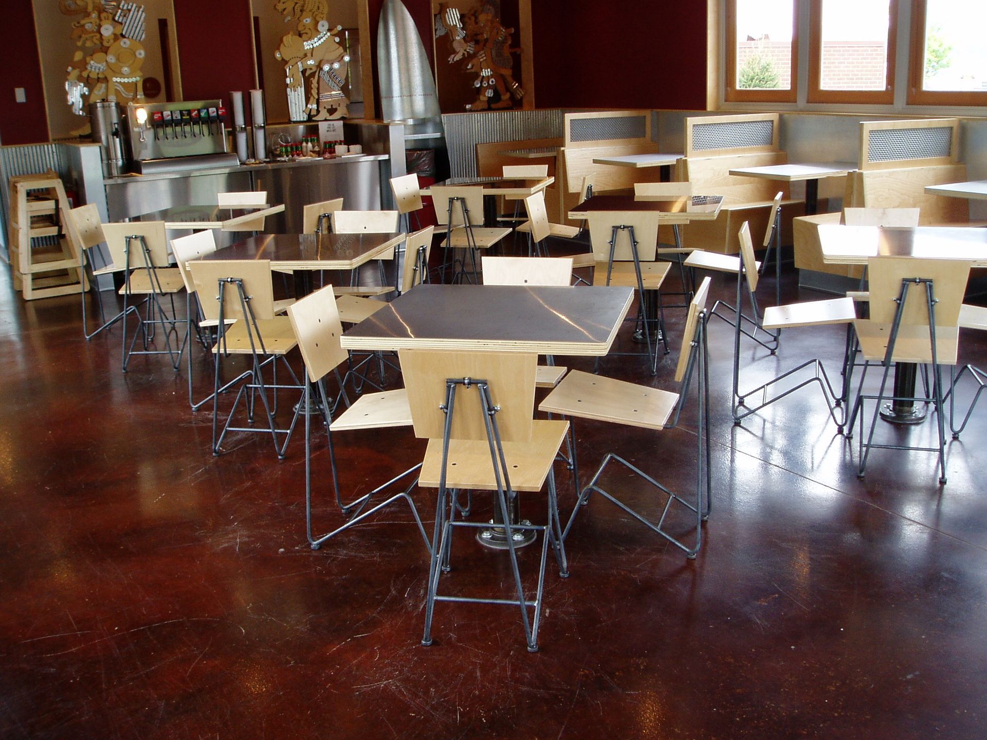 Restaurant interior with tables and chairs on a dark, reddish-brown floor.