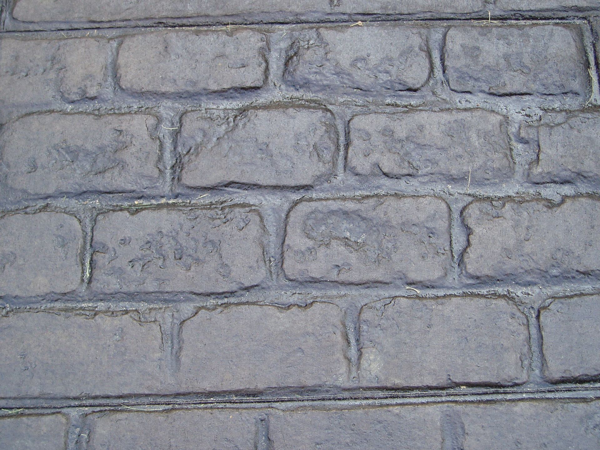Close-up view of a grey brick wall with visible mortar and uneven brick surfaces.