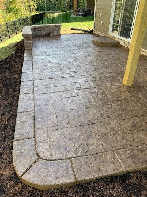Stamped concrete patio with stone border and a small step.