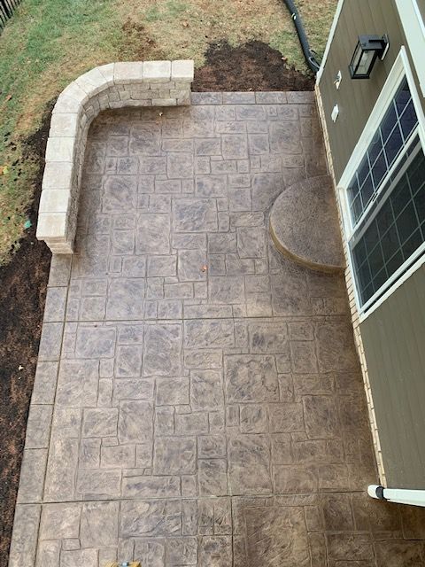 Concrete patio with decorative stamping, retaining wall, and house.