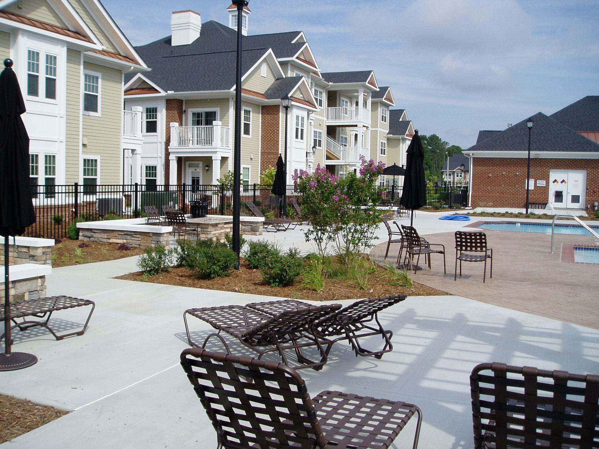 Apartment complex with lounge chairs near a pool on a sunny day.