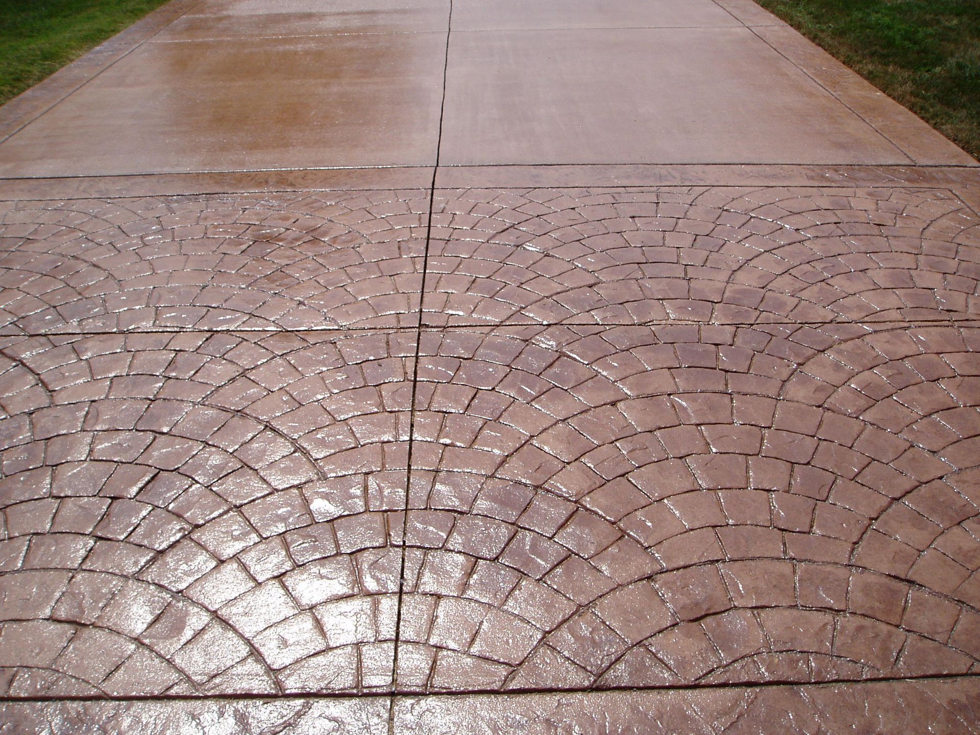 Stamped concrete driveway with a brown, fan-like brick pattern.