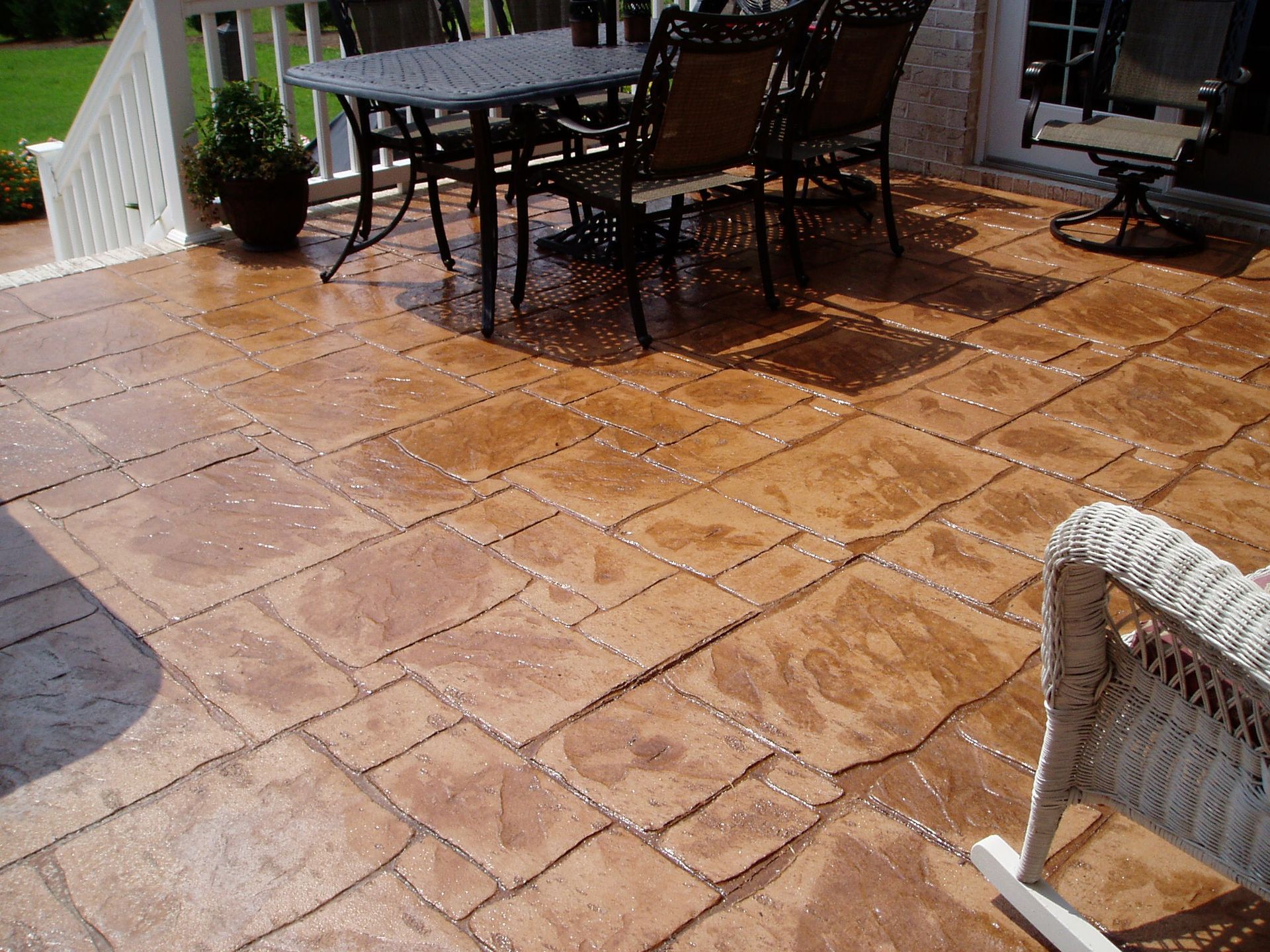 Stamped concrete patio with outdoor furniture; brown hues, sunny day.