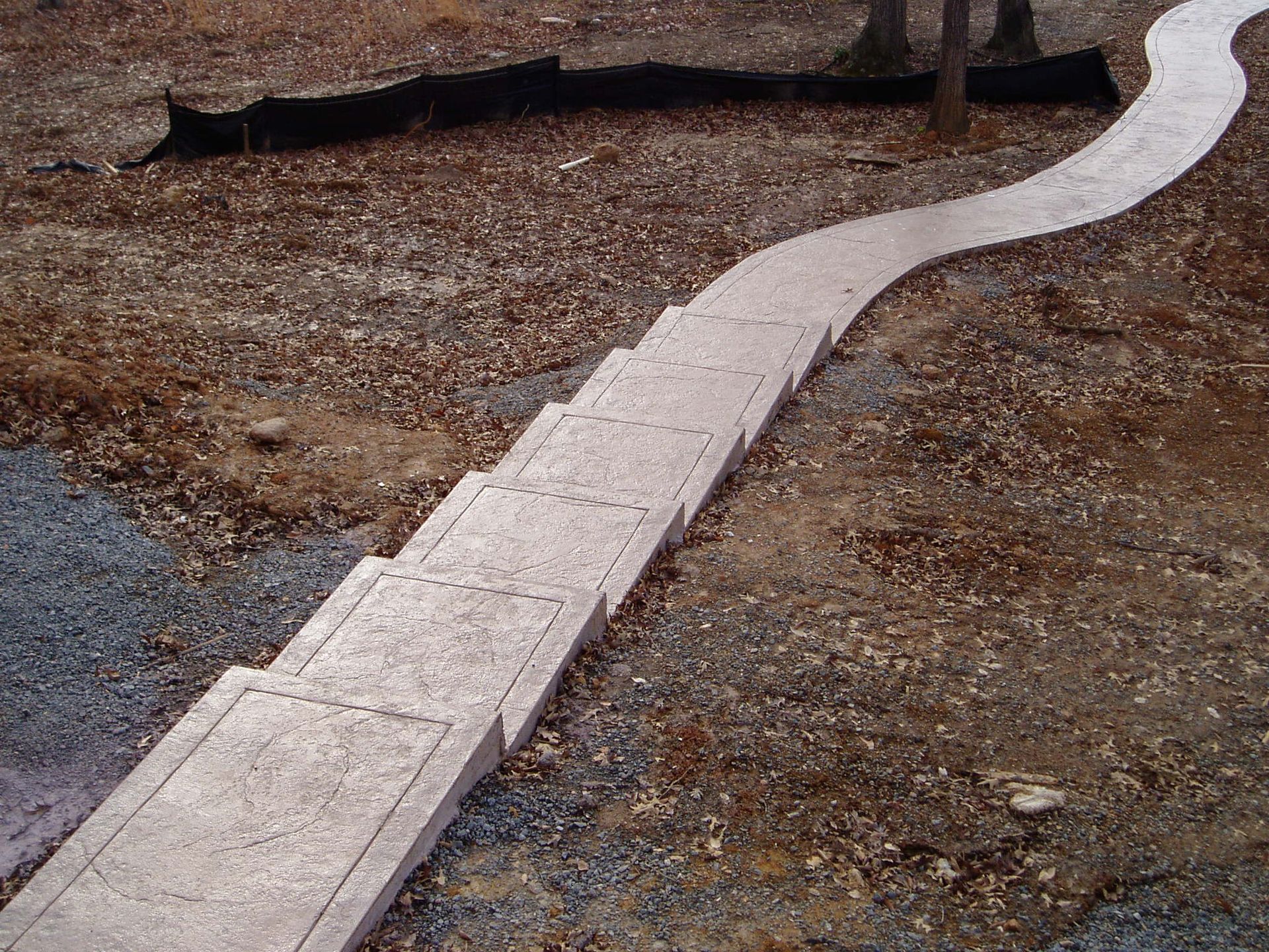 Concrete path with stairs, winding through a brown, rocky outdoor area.