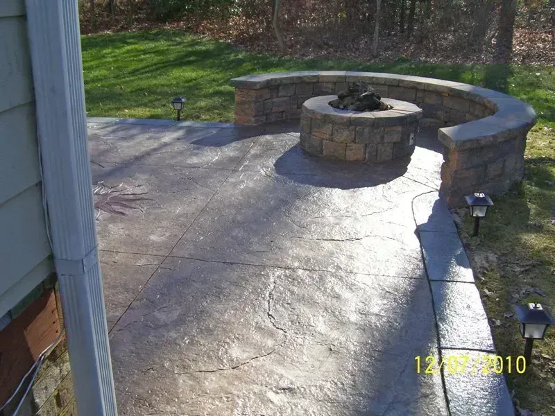 Concrete patio with a circular fire pit and seating wall, with solar lights.