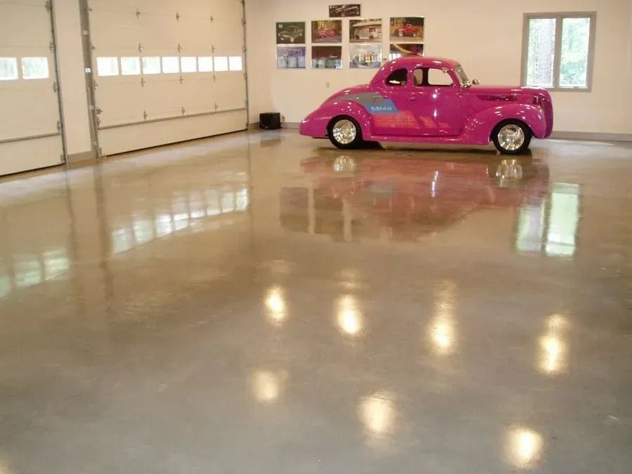Polished concrete garage with a shiny pink classic car.