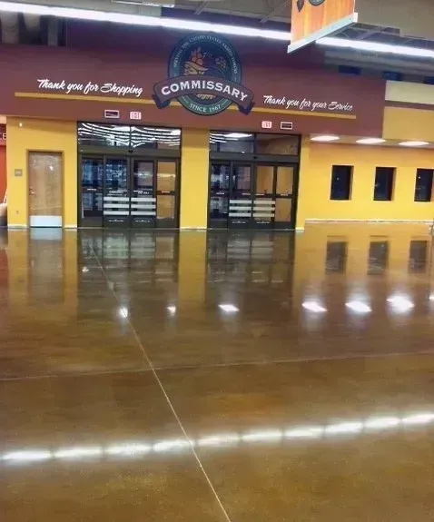 Entrance to a Commissary, with reflective, polished brown floor. Yellow walls, glass doors, and signage.