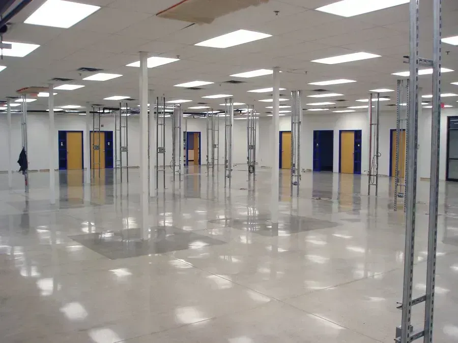 Empty retail space with metal shelving frames, white walls, and multiple doors.