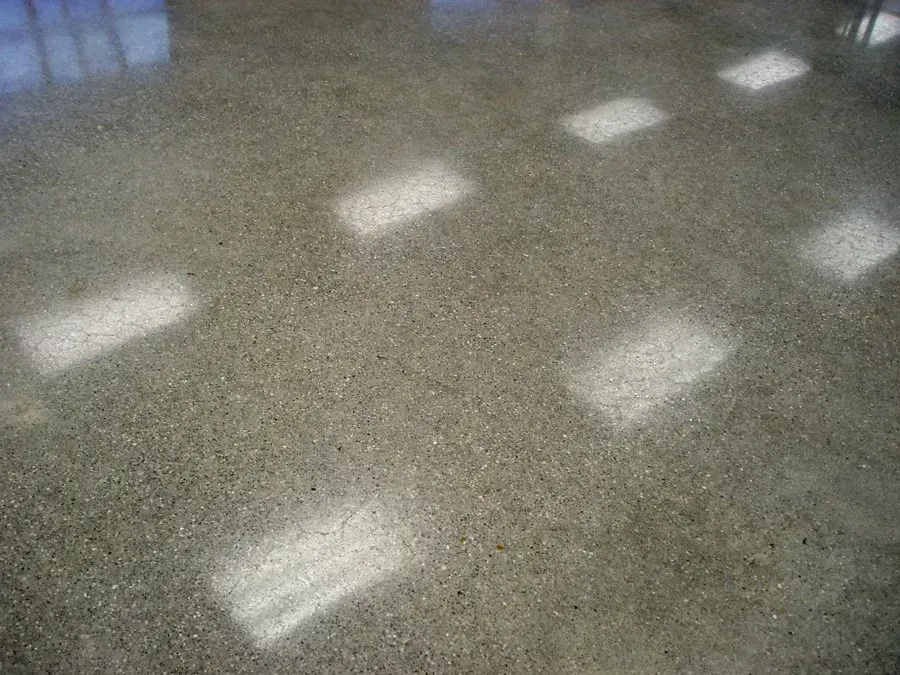 Polished concrete floor reflecting bright rectangular light sources.