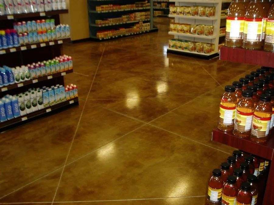 Interior of a grocery store with brown, stained concrete floors and shelves stocked with products.