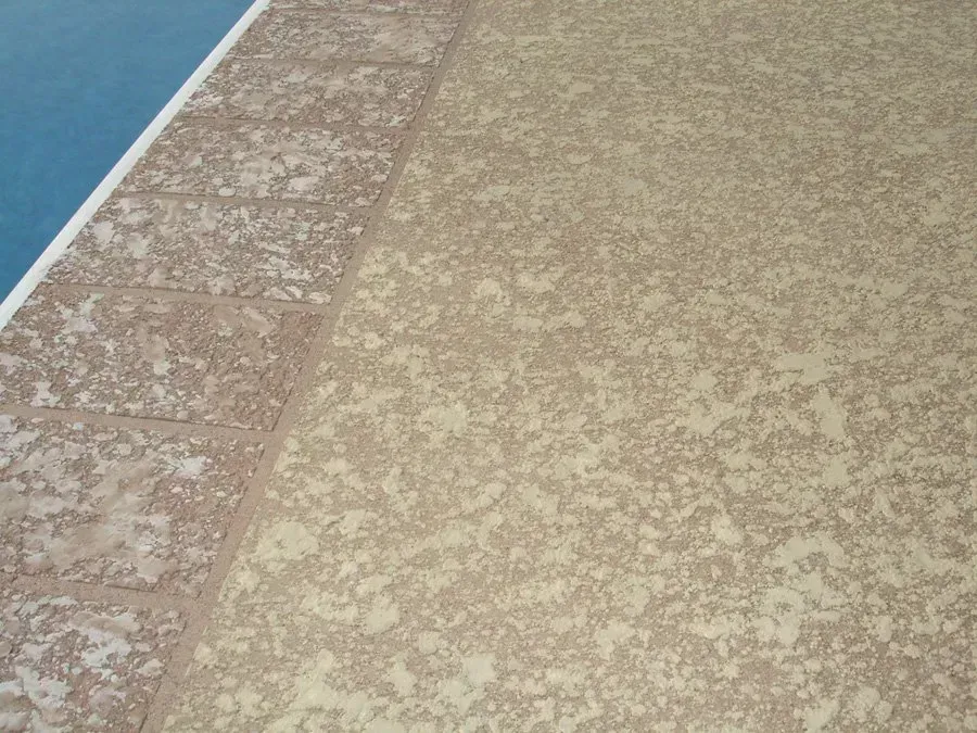 Poolside concrete with textured, light brown surface and brick border.