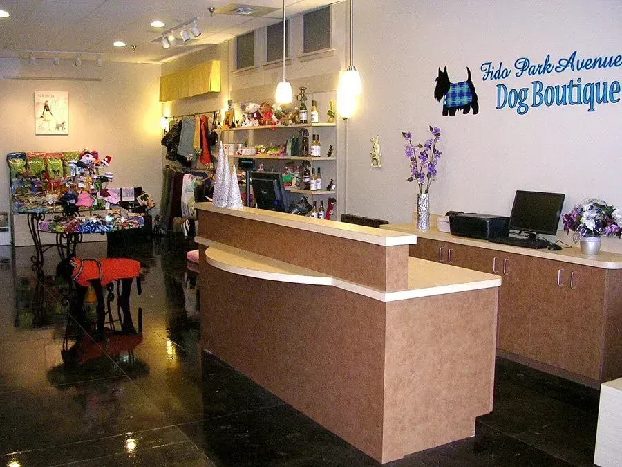 Interior of a dog boutique with a counter, merchandise displays, and a sign.