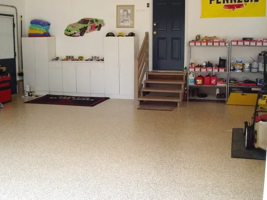 Garage interior with speckled floor, cabinets, shelves, a race car decal, and a Pennzoil flag.