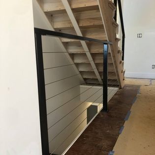 A wooden staircase with a black railing in a room.
