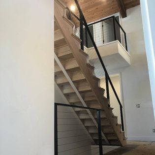 A wooden staircase with a black railing in a house.
