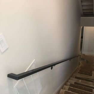 A staircase with a black railing and a white wall.