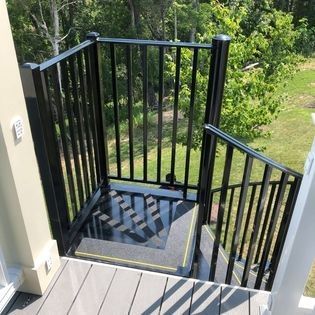 A staircase with a black railing leading up to a deck.