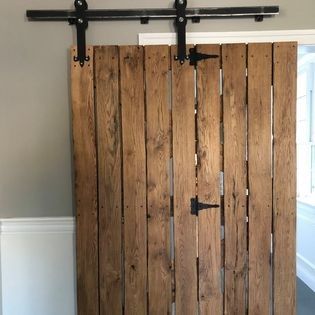 A wooden sliding barn door is hanging on a wall in a room.