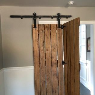 A wooden sliding barn door is hanging on a wall in a room.