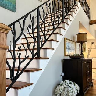 A staircase with a wrought iron railing that looks like a tree.