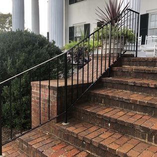 A set of stairs with a metal railing leading up to a house.