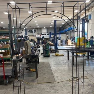 A large metal arch is being built in a garage.