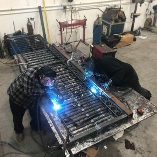 A man is welding a piece of metal in a workshop.