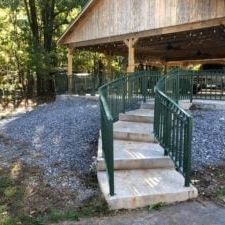 A set of stairs leading up to a wooden building with a green railing.