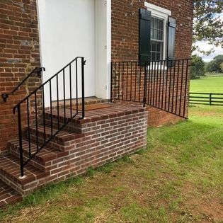A brick building with stairs and a wrought iron railing.