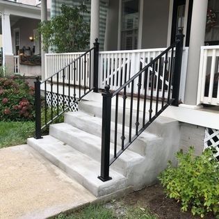 A black wrought iron railing on a porch of a house.