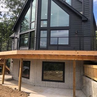 A black house with a wooden deck on the side of it.
