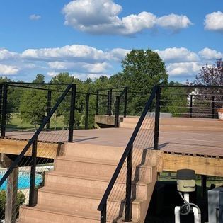 A deck with stairs leading up to it and a swimming pool in the background.