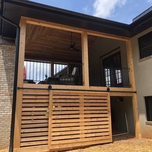 A large wooden porch with a sliding barn door and a ceiling fan.